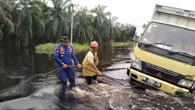 Perwira Polres Pelalawan Bantu Tarik Mobil Box Terperosok di Lokasi Banjir